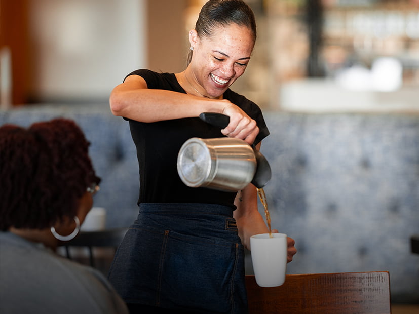 Server laughs with cutomer as she pours coffee